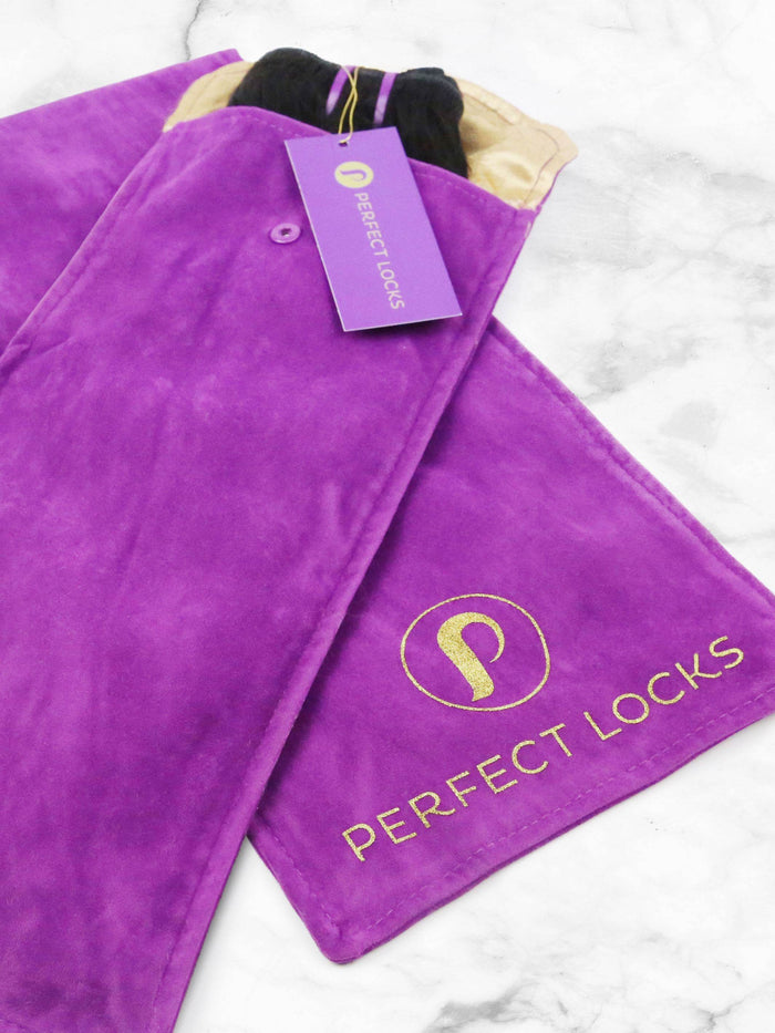 A purple suede pouch with gold Perfect Locks branding sits on marble, partially open to reveal a Curly Swiss Lace Closure inside.