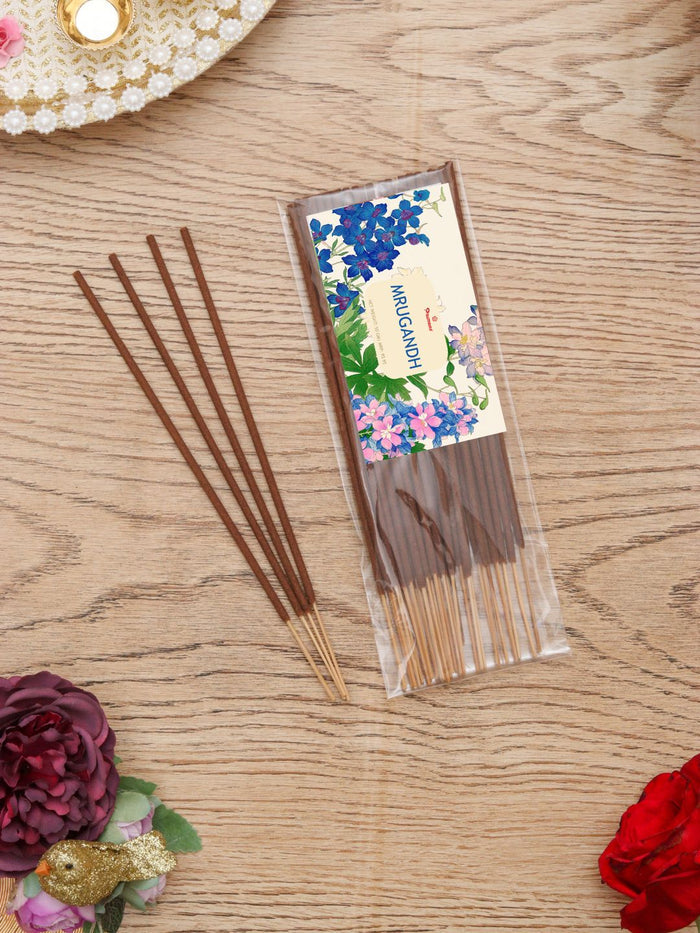 Individual pack of incense sticks with floral label, with loose sticks beside it