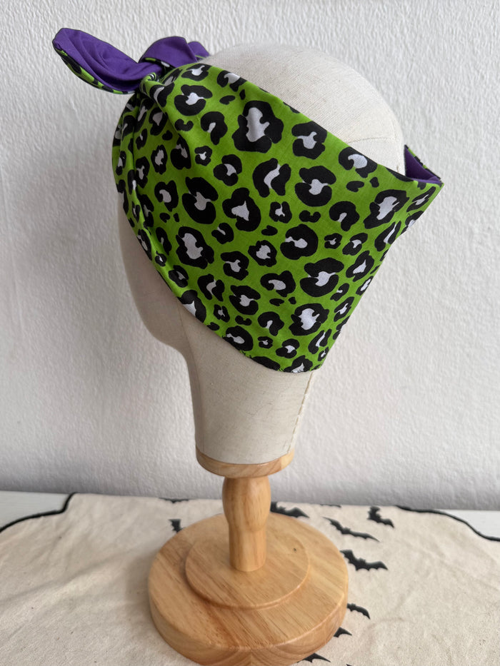 Green leopard print headscarf with purple accents on a mannequin head against a white background