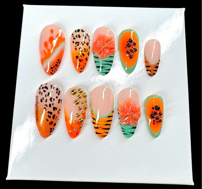 A set of ten decorative press-on nails displayed on a white backing card against a black background. The nails feature tropical and animal-inspired designs including orange gradients, leopard prints, floral motifs, and tiger stripes.