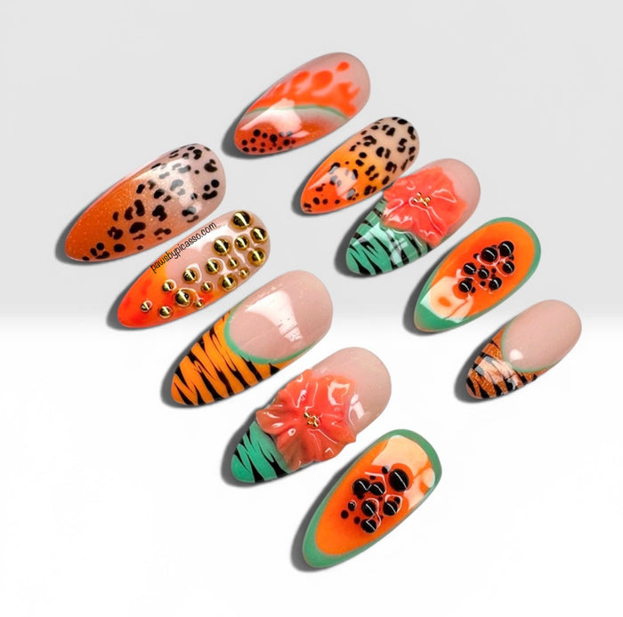 Ten false press-on nails with various designs including leopard print, tiger stripes, orange and green tropical patterns, and metallic gold studs, arranged on a light gray background.