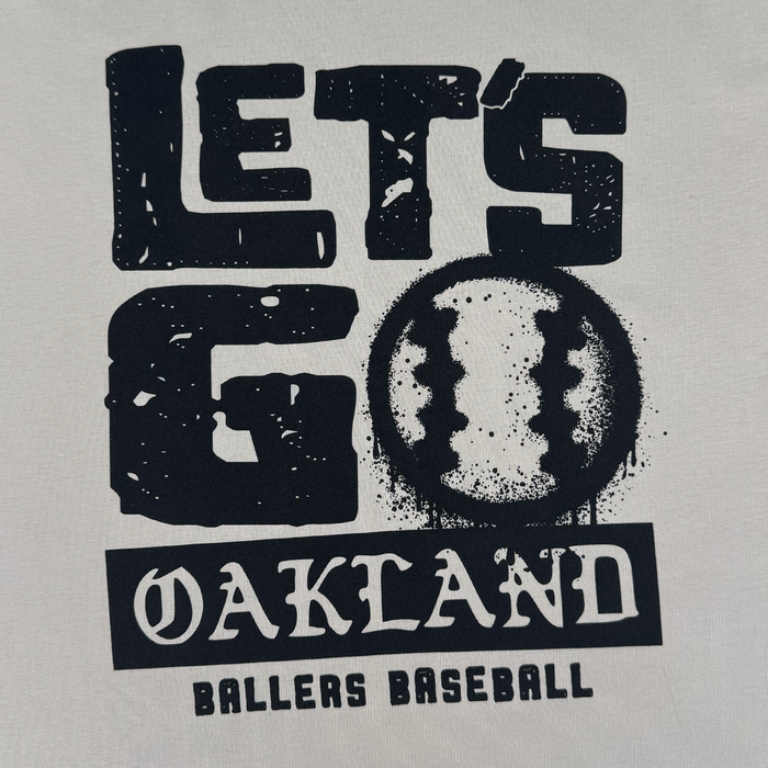 The Let's Go Oakland Tee by Oakland Ballers features black text on white, with “LET'S GO OAKLAND BALLERS BASEBALL” and a baseball-styled “O,” reflecting the team’s Pioneer League spirit and East Bay heritage.