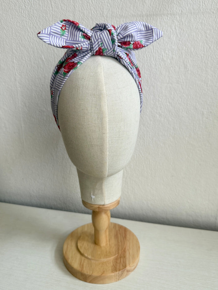 Floral headband on a mannequin head against a plain background