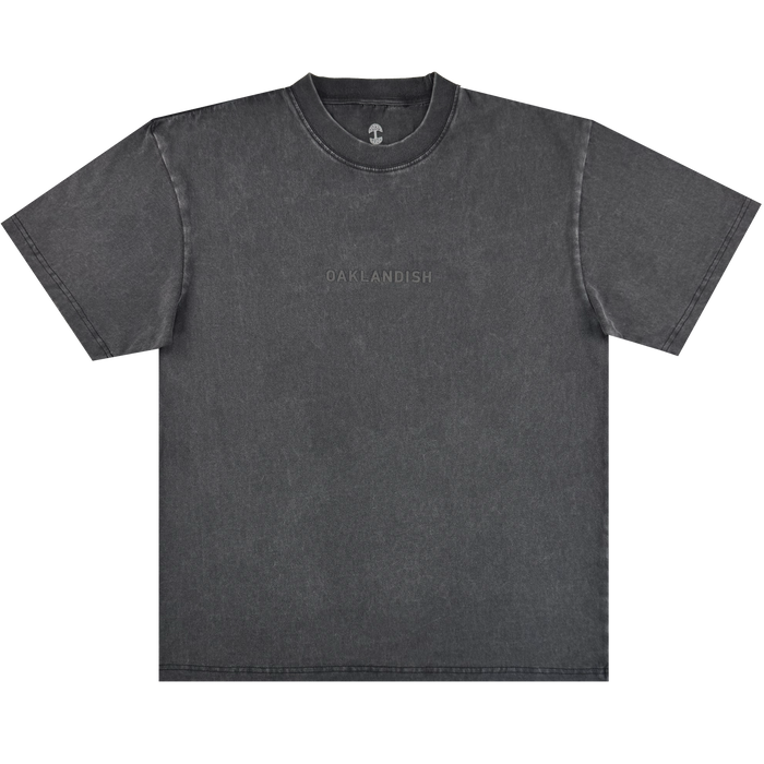 The Oaklandish Classic Logo Tee by Oaklandish is a heavyweight black cotton shirt with "OAKLANDISH" subtly printed across the chest. It features a classic crew neckline and visible stitched seams, shown laid flat on a light background.