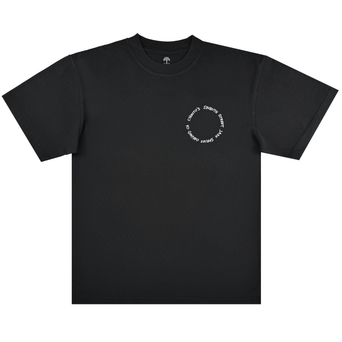 A plain black Ode to Jass Tee by Other lies flat on a white background. On the upper left chest, white text forms a small circle that repeatedly reads “Stems and Gems”—a subtle tribute to Oakland jazz and its influence on style.