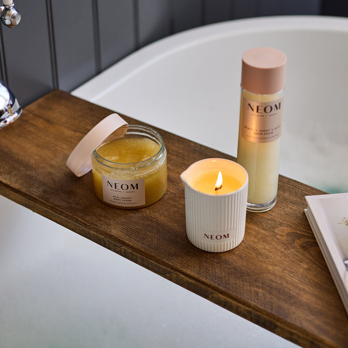 NEOM body scrub, intensive skin treatment candle and bath foam on a shelf in the bath