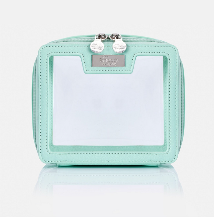 A light green, smooth travel bag with a zipper closure and a brand tag on the side.