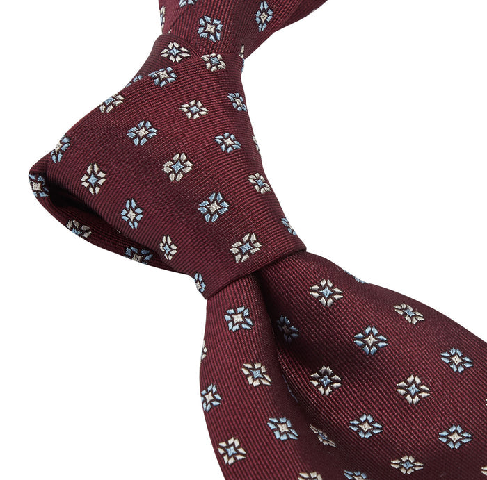 A Sovereign Grade Oxblood Square Floral Jacquard Tie by KirbyAllison.com, featuring blue and white flowers, showcasing quality craftsmanship.