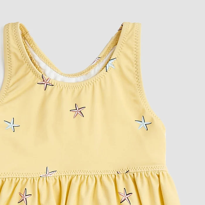 Closeup of Miles The Label starfish swimsuit showing Sunrise Yellow fabric, frilly trim, and stretch material.