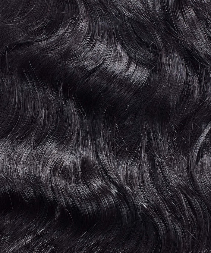 A close-up of long, wavy, shiny black hair in Natural Black  with Perfect Locks' extensions, showing smooth texture and waves.
