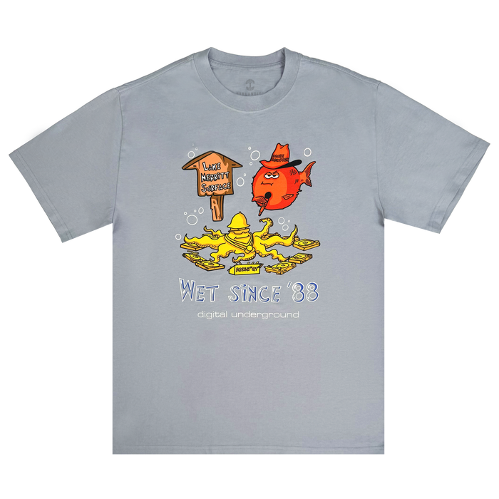 Light gray “Wet Since ’88 Heavy Tee” by Other, featuring a cartoon red fish and yellow duck beneath a wooden sign that reads “Lakes Health Spa 2024,” surrounded by bubbles. The playful design includes blue and white text: “Wet Since ’88” and “digital underground”—a tribute to Oakland’s legendary group, Digital Underground.