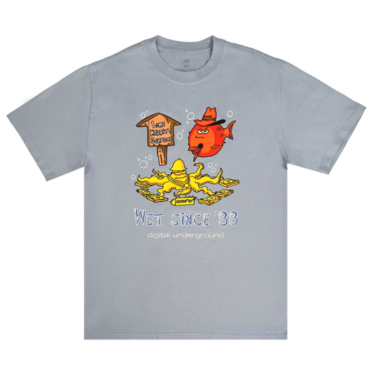 Light gray “Wet Since ’88 Heavy Tee” by Other, featuring a cartoon red fish and yellow duck beneath a wooden sign that reads “Lakes Health Spa 2024,” surrounded by bubbles. The playful design includes blue and white text: “Wet Since ’88” and “digital underground”—a tribute to Oakland’s legendary group, Digital Underground.