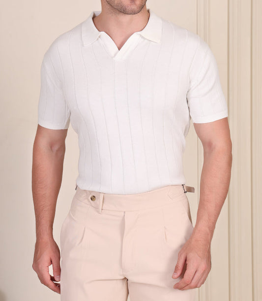Man wearing a white polo shirt and beige pants against a neutral background